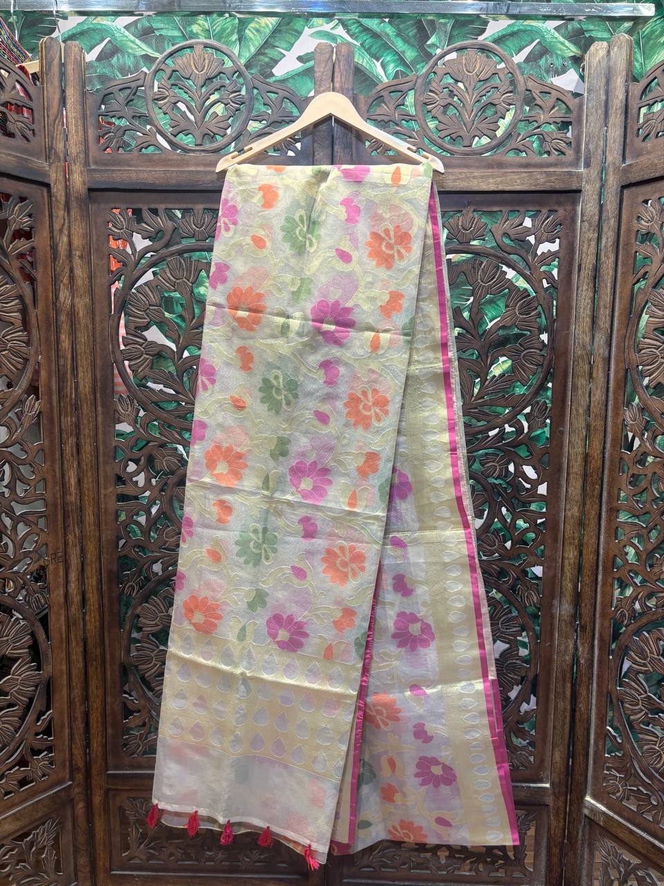 Floral patterned fabric hanging on a wooden hanger against a decorative wooden background