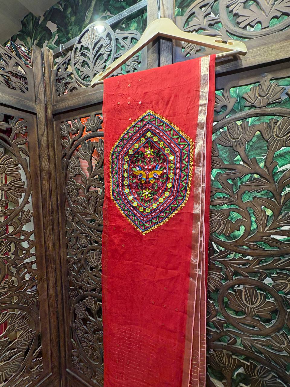 A detailed view of the sheer red organza fabric, showing the elegant Zari border and subtle woven butis on the body of the saree.