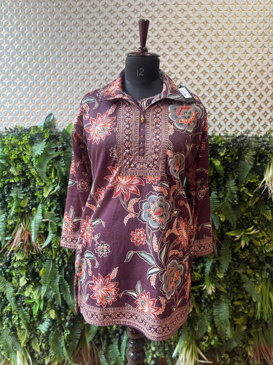 Floral patterned shirt on a mannequin against a textured wall and green foliage background