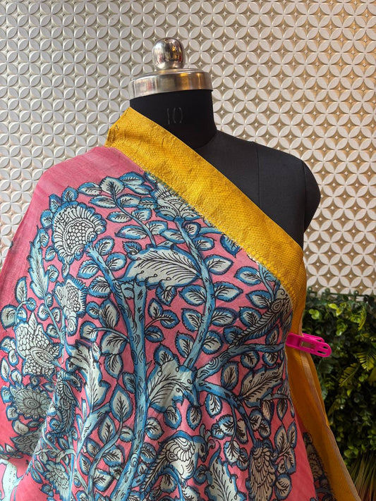 A close-up shot of the pink Kalamkari dupatta draped on a mannequin, highlighting the texture of the cotton-silk fabric and the blue floral print.