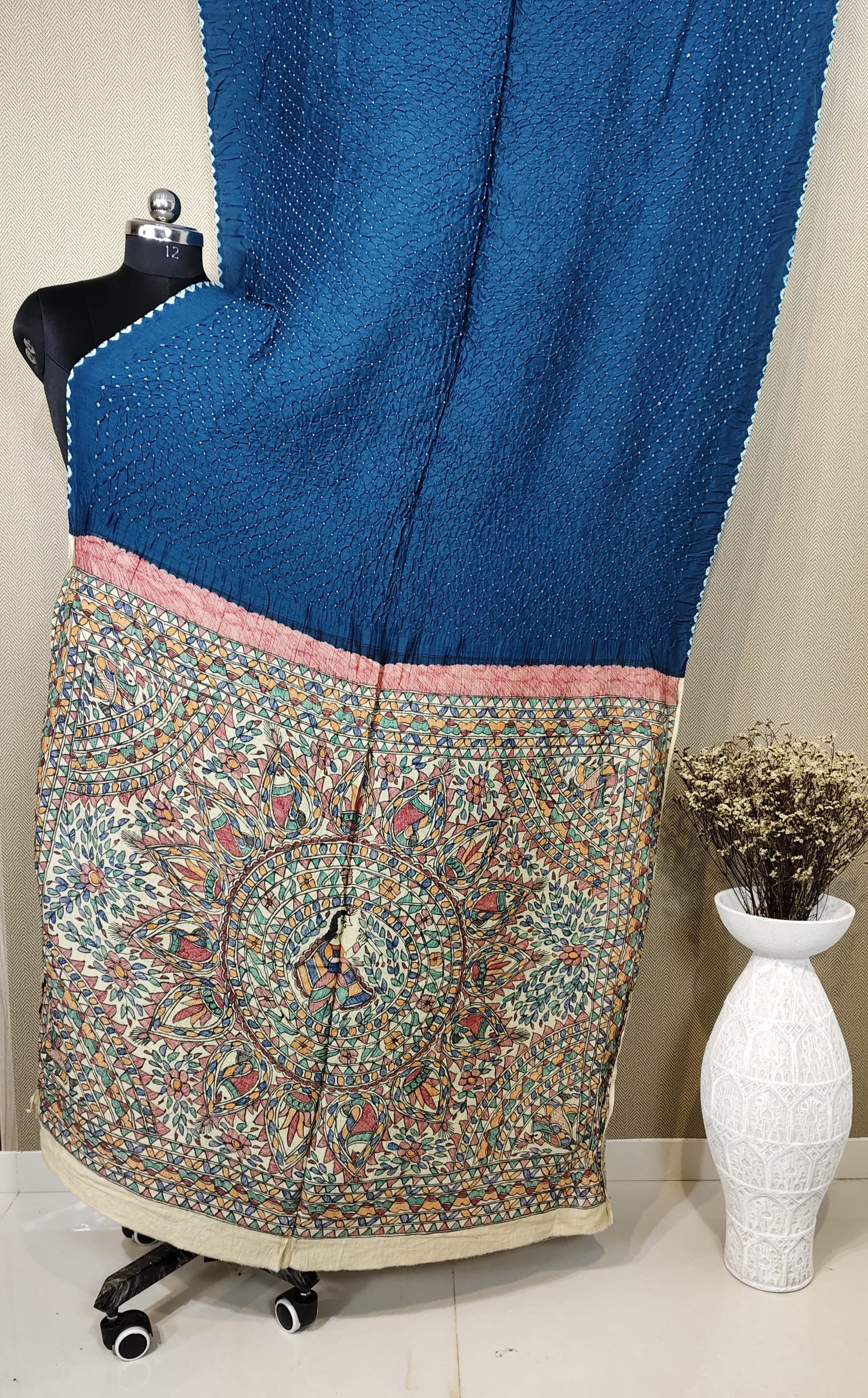 An indigo blue Munga silk saree with a fine Bandhani body and a hand-painted Kalamkari pallu featuring a large, detailed mandala motif.