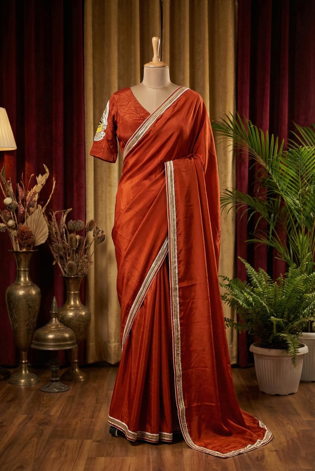 Rust silk bridal saree with embellished border draped on mannequin.