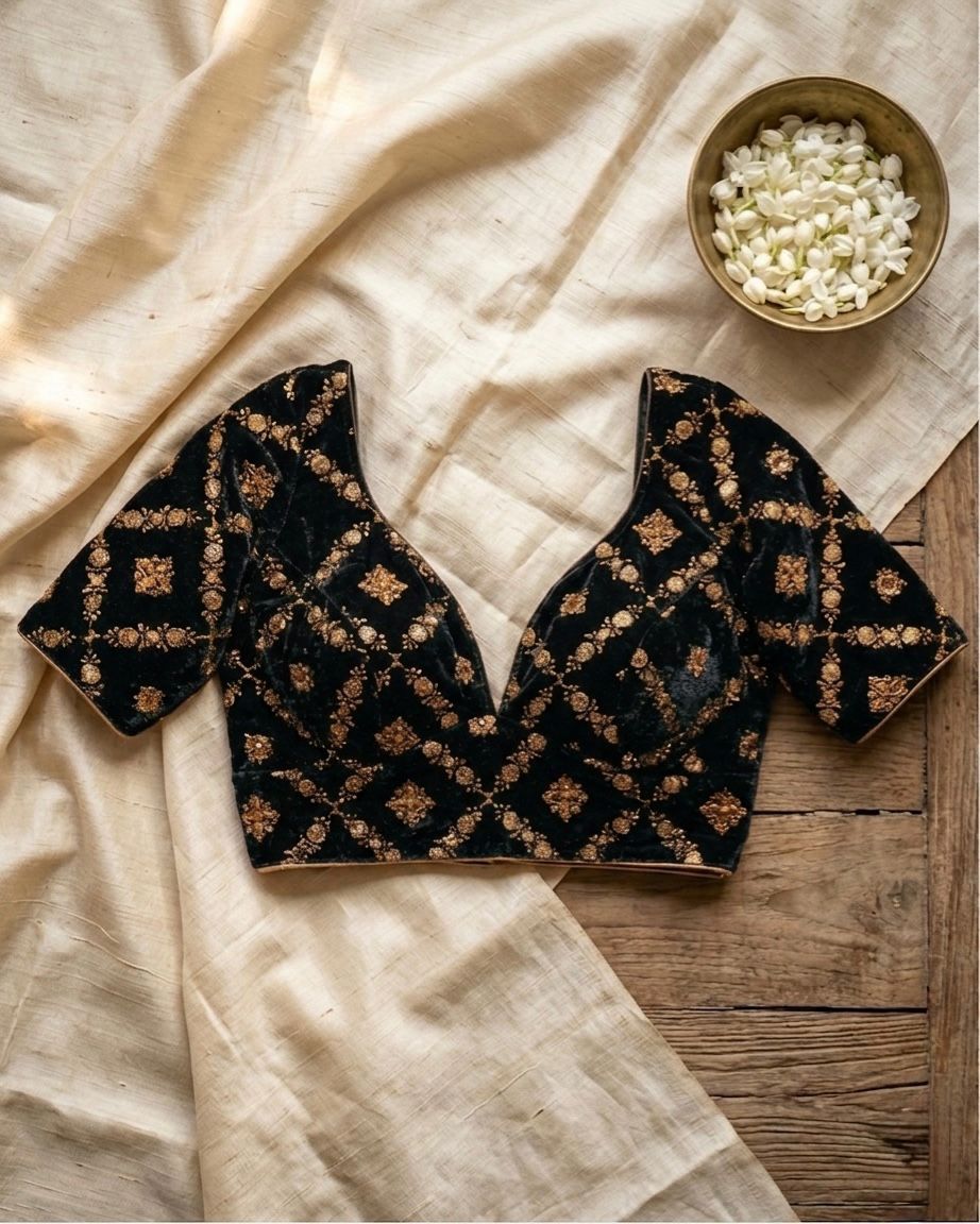 Black embroidered top on a wooden surface with a bowl of white flowers.
